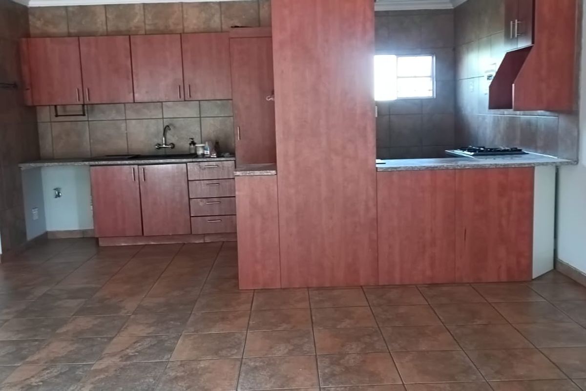 A functional kitchen featuring built-in cabinetry, laminate countertops, a gas hob, and tiled flooring throughout.