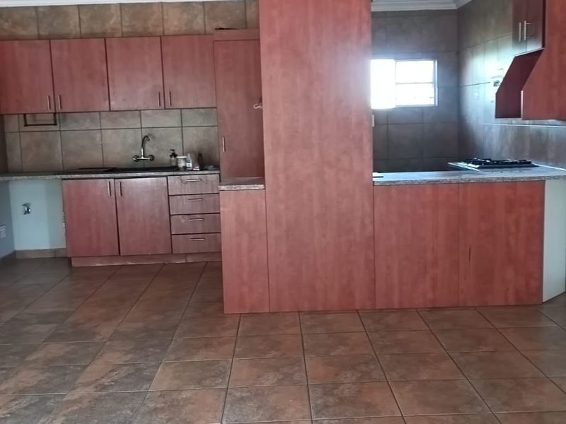 A functional kitchen featuring built-in cabinetry, laminate countertops, a gas hob, and tiled flooring throughout.