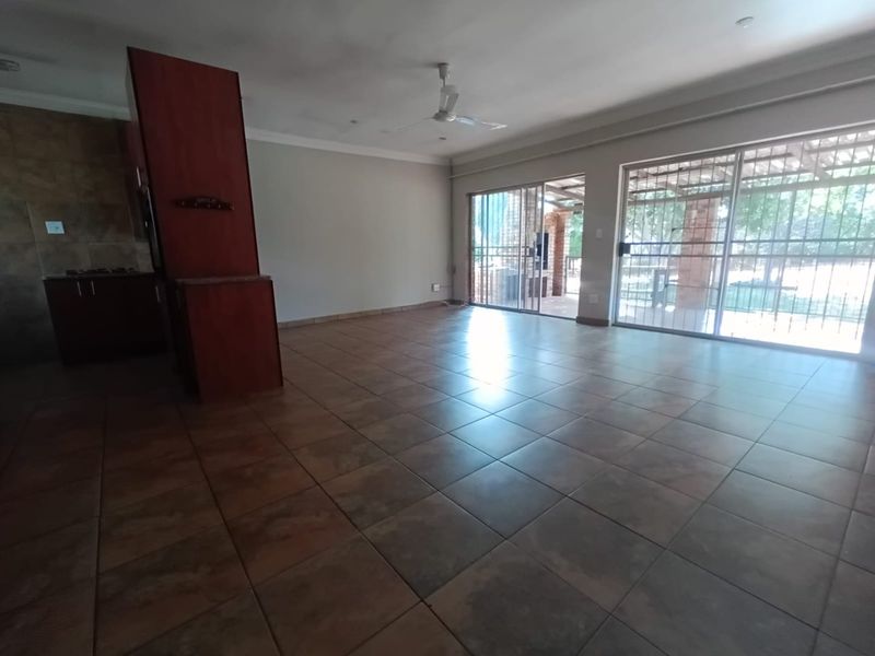 Spacious open-plan living area featuring tiled flooring, a ceiling fan, and large sliding glass doors providing access to the outdoor patio area.