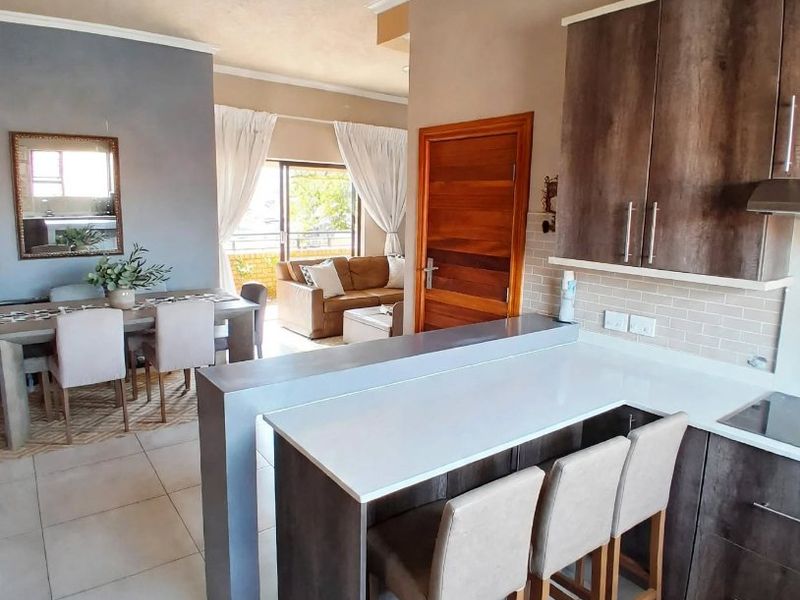 Modern open-plan living area featuring a well-appointed kitchen with stone countertops, breakfast bar, and seamless flow to the dining and lounge spaces.