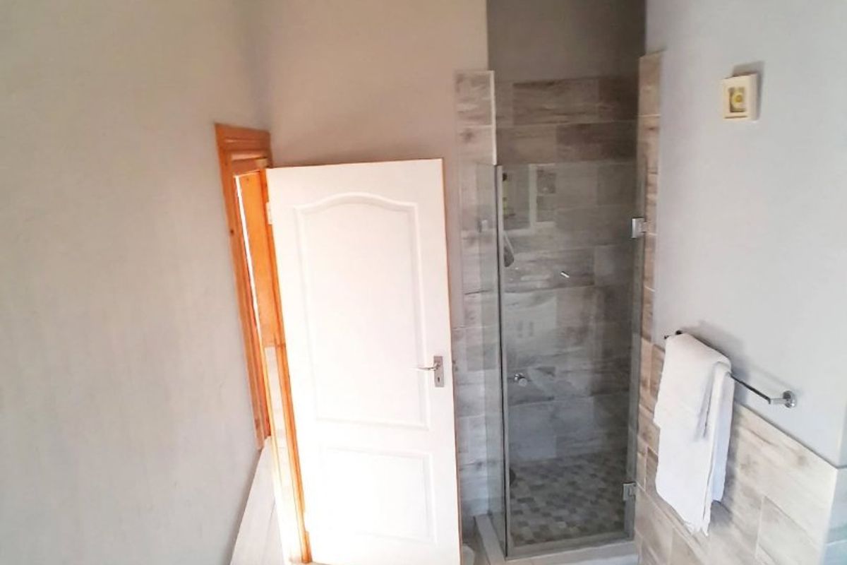 A functional bathroom featuring a built-in bathtub, a separate shower enclosure with tiled walls, and neutral floor tiling.