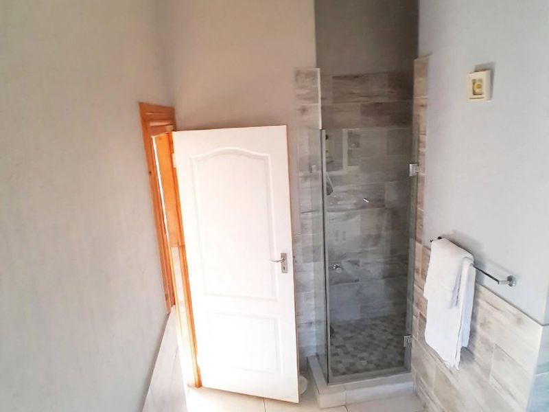 A functional bathroom featuring a built-in bathtub, a separate shower enclosure with tiled walls, and neutral floor tiling.