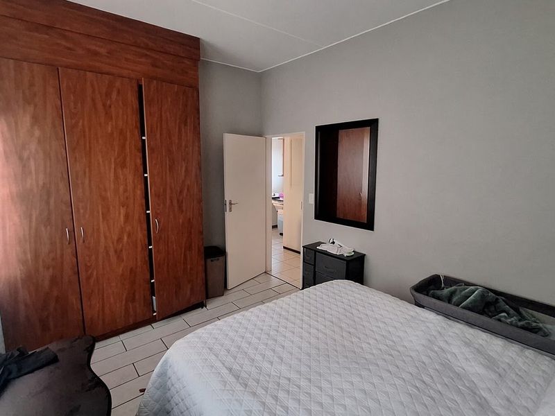 A bedroom featuring tiled flooring and a large built-in wooden wardrobe, providing ample storage space.