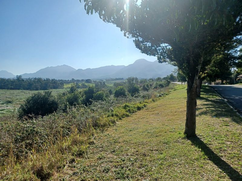 A scenic view of the surrounding landscape and distant mountains, captured from the roadside of the vacant residential property.