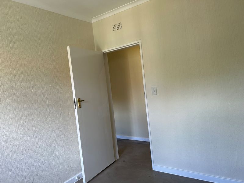 An empty bedroom featuring textured walls, coving, and a standard internal door leading to an adjacent space.