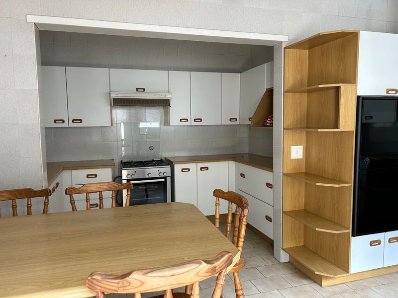 A functional kitchen featuring white cabinetry, a gas stove with extractor fan, and tiled splashbacks, offering a practical layout for daily cooking.