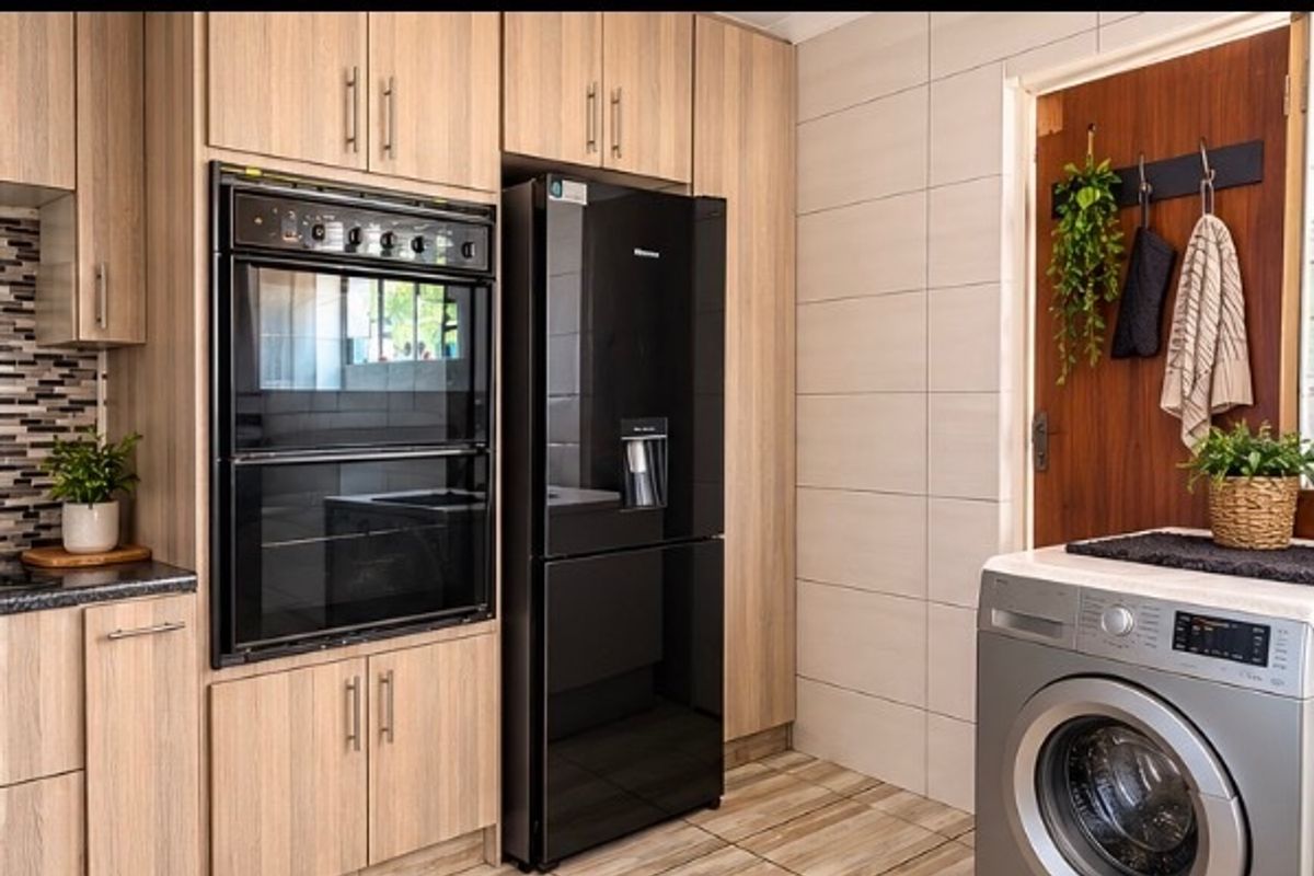Modern kitchen featuring light wood-grain cabinetry, built-in double oven, tiled splashback, and neutral wall tiles, providing a clean and functional cooking space.