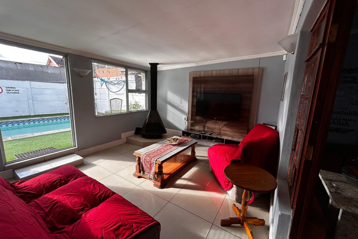 A living room featuring tiled floors, a freestanding fireplace, and a built-in media wall, with direct access to the pool area through sliding glass doors.