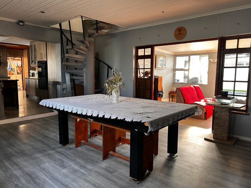 Open plan living area featuring a spiral staircase, laminate flooring, and direct access to an adjacent kitchen and secondary living space.