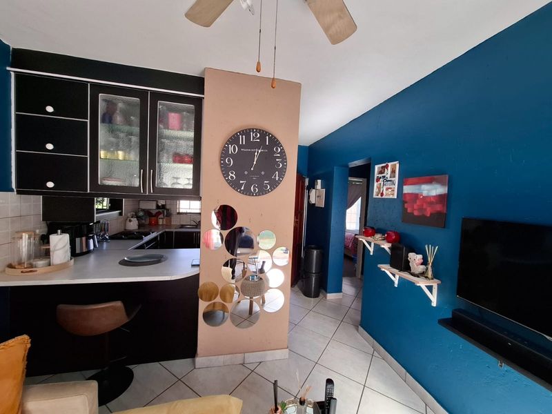 Open plan living area featuring a kitchen with built-in cabinetry and tiled flooring, connecting to the main living space.
