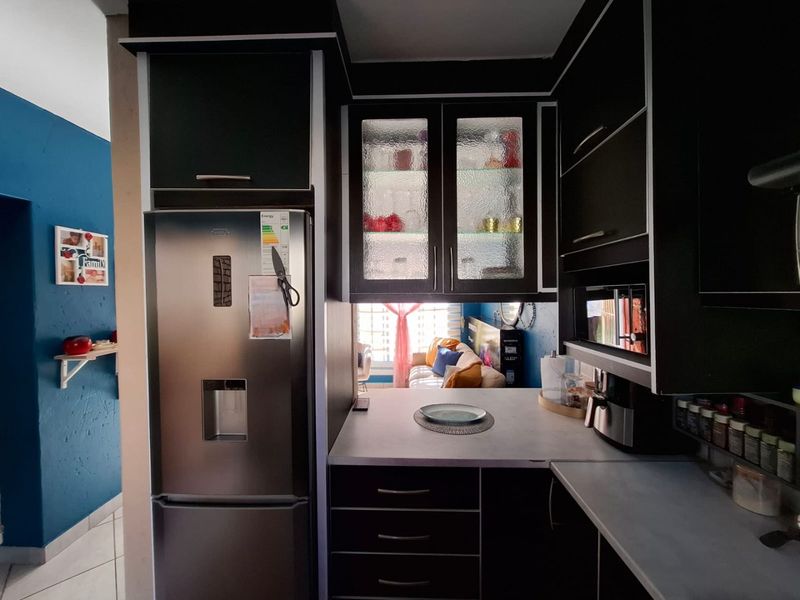 A compact kitchen featuring dark modern cabinetry, glass-fronted upper storage, and integrated microwave, providing a functional and stylish cooking space.