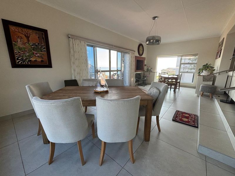 Spacious dining area featuring large sliding glass doors, tiled flooring, and a built-in fireplace, offering a bright and open living environment.