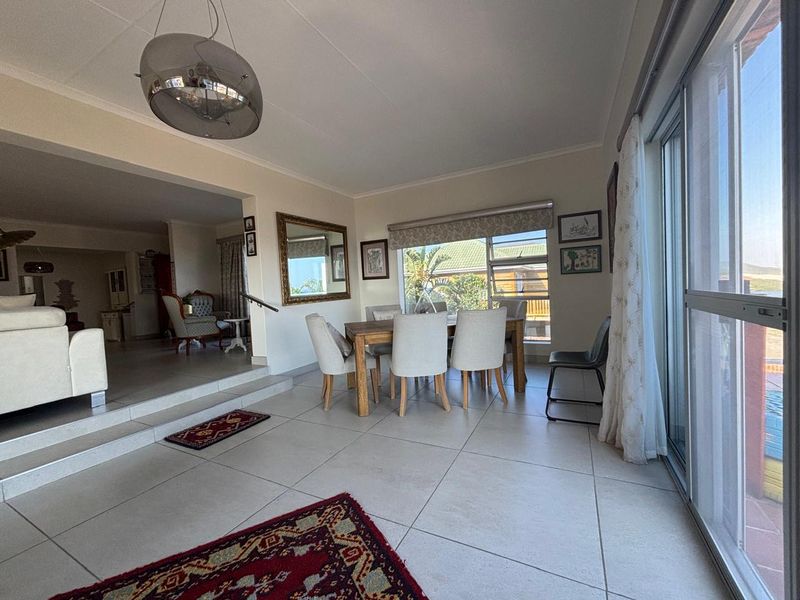 Spacious open-plan living and dining area featuring large format floor tiles, a stepped transition between levels, and expansive sliding glass doors leading outdoors.