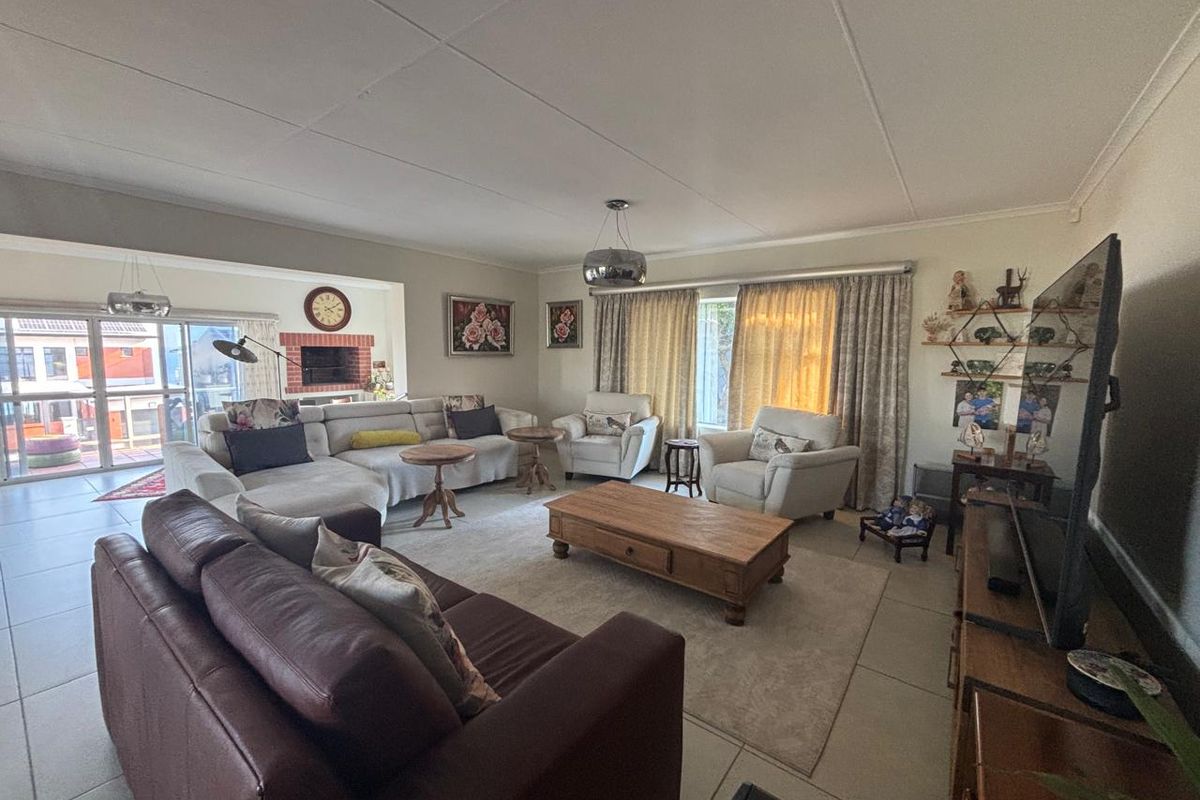 Spacious living room featuring tiled flooring, a built-in brick fireplace, and large sliding glass doors providing access to the outdoor area.