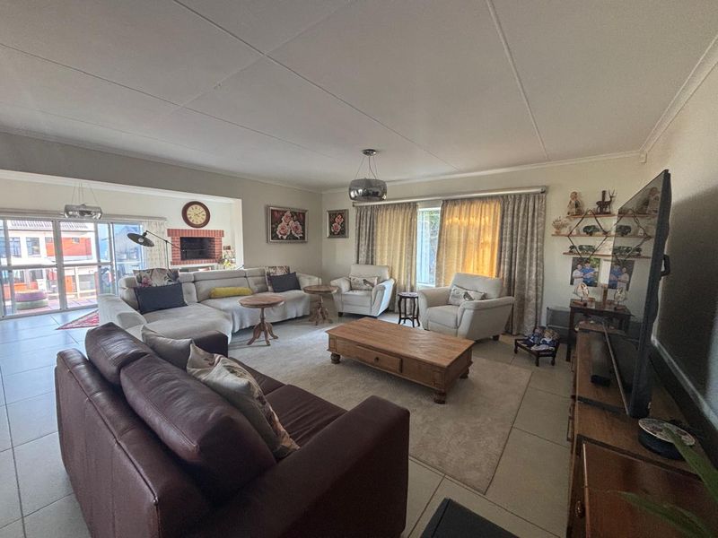 Spacious living room featuring tiled flooring, a built-in brick fireplace, and large sliding glass doors providing access to the outdoor area.