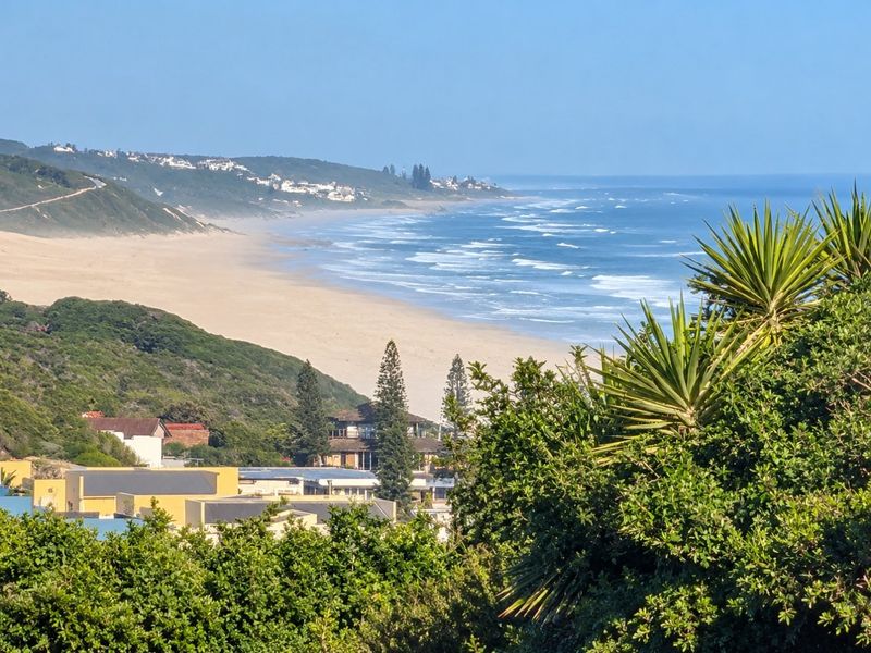 A scenic elevated view overlooking the coastline, sandy beach, and surrounding natural landscape.