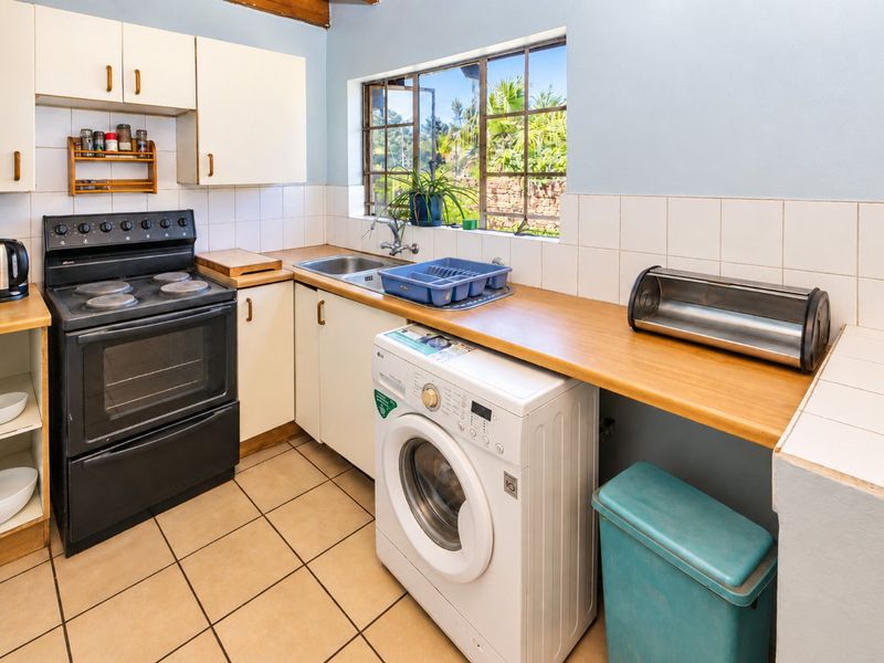 Functional kitchen featuring built-in cabinetry, electric stove, oven, stainless steel sink, and tiled flooring with a practical layout.