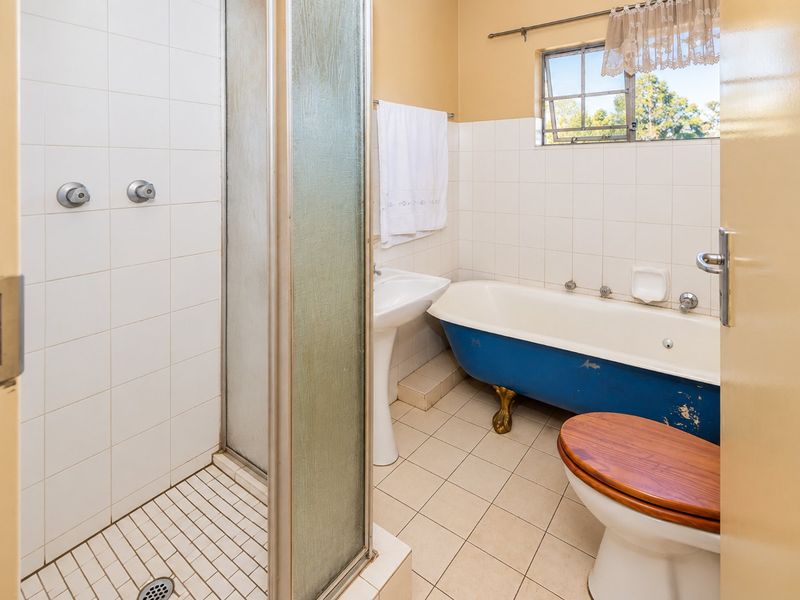 A dated bathroom featuring a clawfoot bathtub, separate shower enclosure, and pedestal basin, offering potential for a modern renovation.