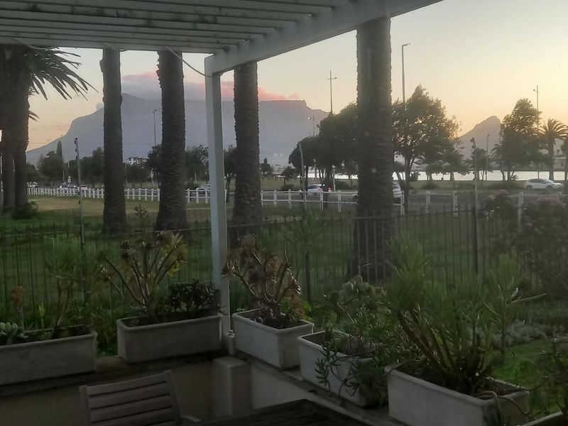 A covered balcony featuring a pergola and built-in planter boxes, offering scenic views of the surrounding landscape and mountains.