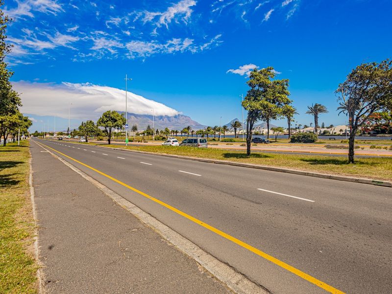 A clear street view showing the main road approach with a scenic mountain backdrop and well-maintained surrounding landscape.