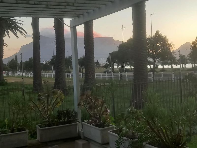 A covered patio area featuring a pergola structure, overlooking a landscaped garden with scenic mountain views.