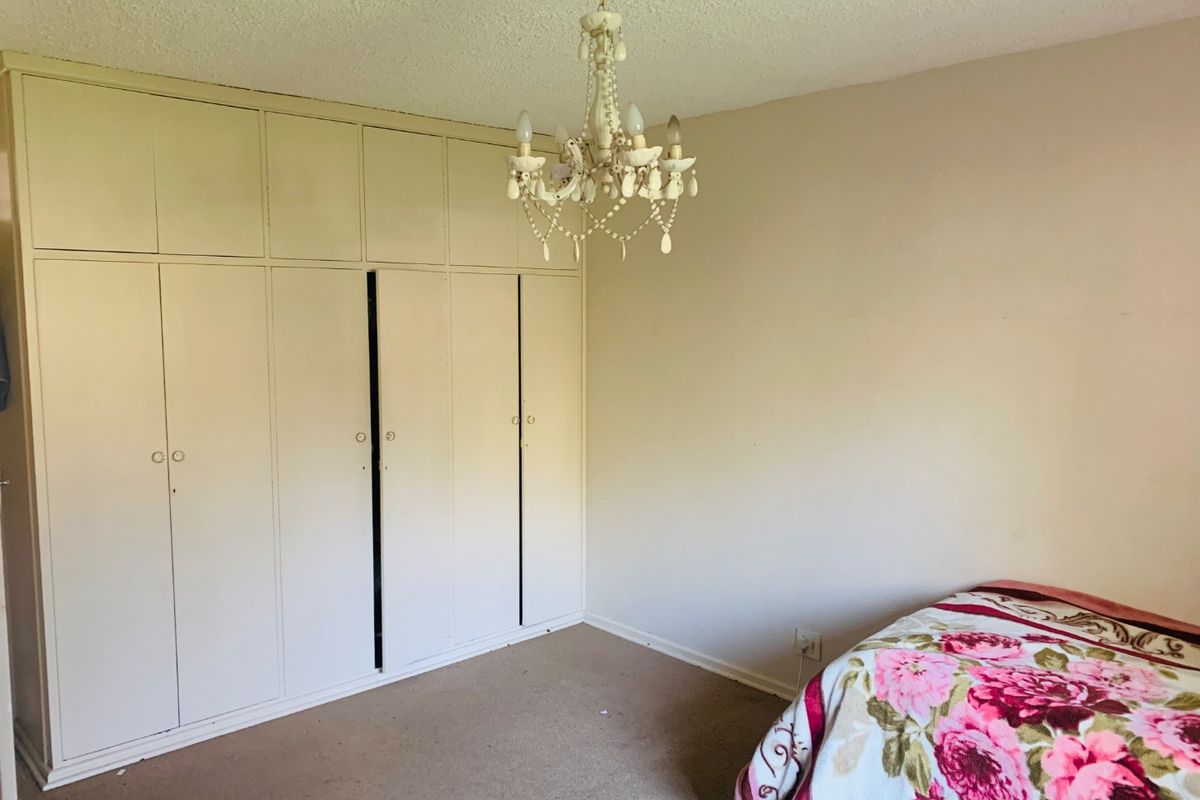 Bedroom featuring extensive built-in floor-to-ceiling cupboards and a decorative chandelier, offering ample storage space.