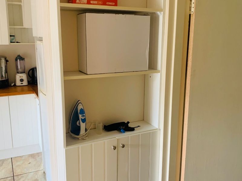 A hallway featuring built-in white cabinetry with open shelving, providing convenient storage space adjacent to the kitchen area.