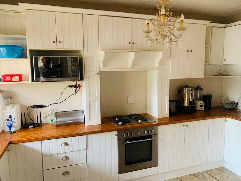 A functional kitchen featuring white cabinetry, wooden countertops, a built-in oven, and an electric hob.