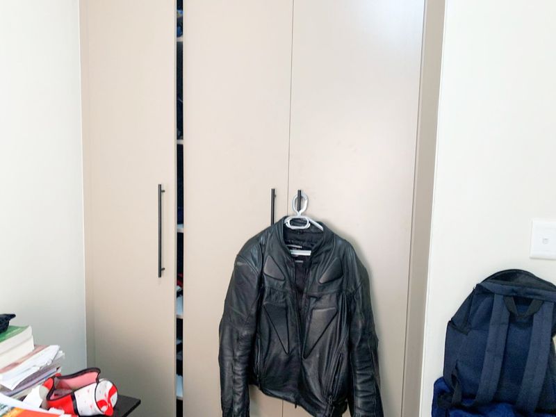 A bedroom featuring a modern, neutral-toned built-in wardrobe with sleek vertical handles.