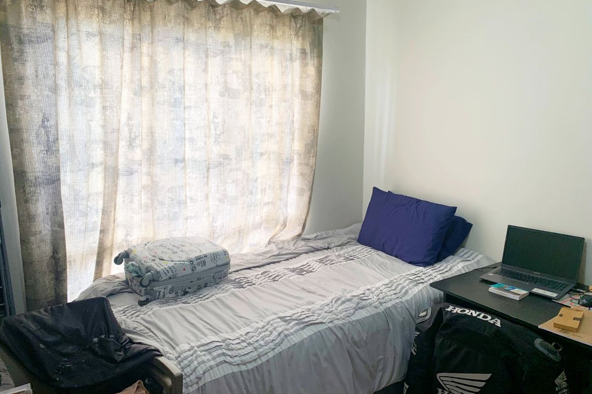 A compact bedroom featuring a large window with a curtain rail, providing natural light to the space.