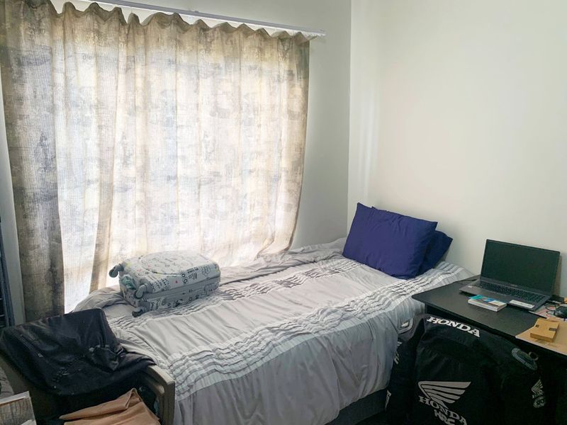 A compact bedroom featuring a large window with a curtain rail, providing natural light to the space.