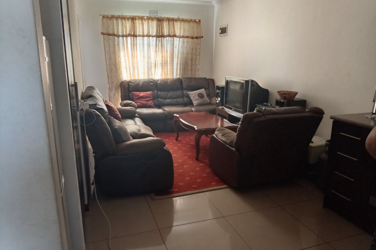 A comfortable living room featuring tiled flooring, recessed ceiling lighting, and coved cornicing, providing a functional space for relaxation.