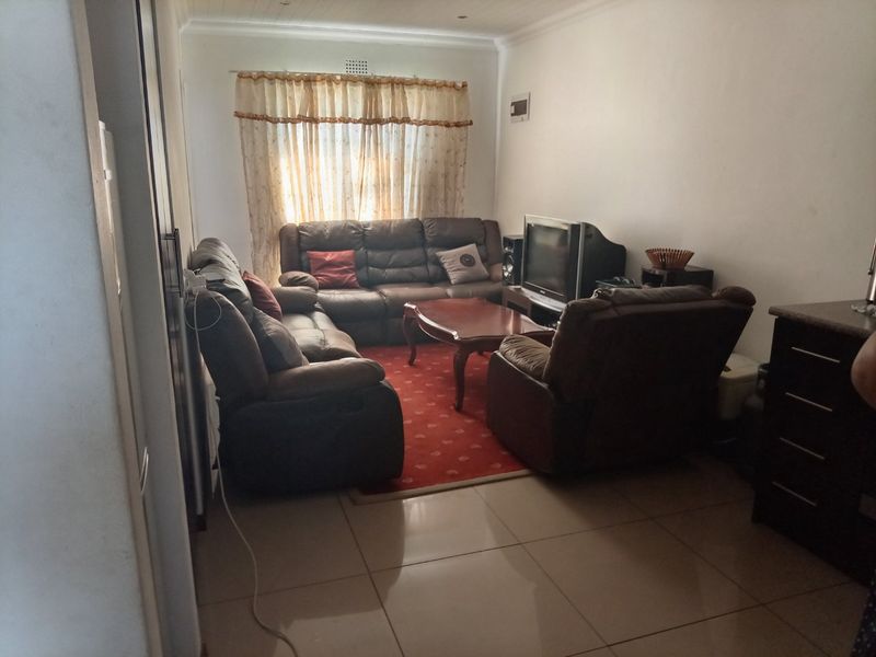 A comfortable living room featuring tiled flooring, recessed ceiling lighting, and coved cornicing, providing a functional space for relaxation.