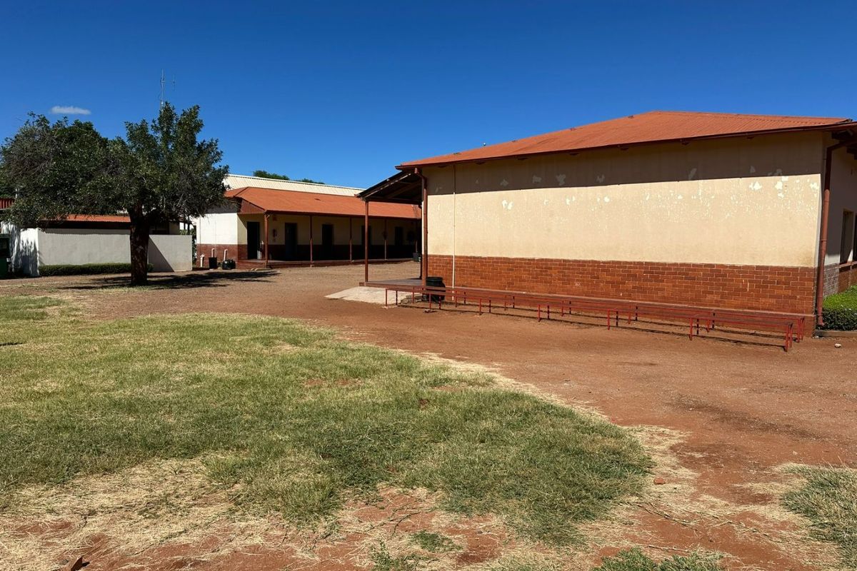 Exterior view of a commercial building complex featuring brick and rendered walls with a corrugated metal roof and a covered walkway area.