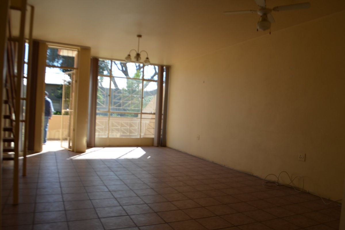 An empty living room featuring tiled flooring, a ceiling fan, and access to an outdoor area through a large glass sliding door.
