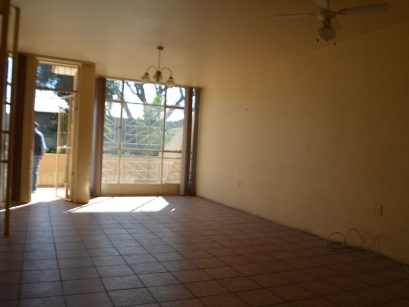 An empty living room featuring tiled flooring, a ceiling fan, and access to an outdoor area through a large glass sliding door.