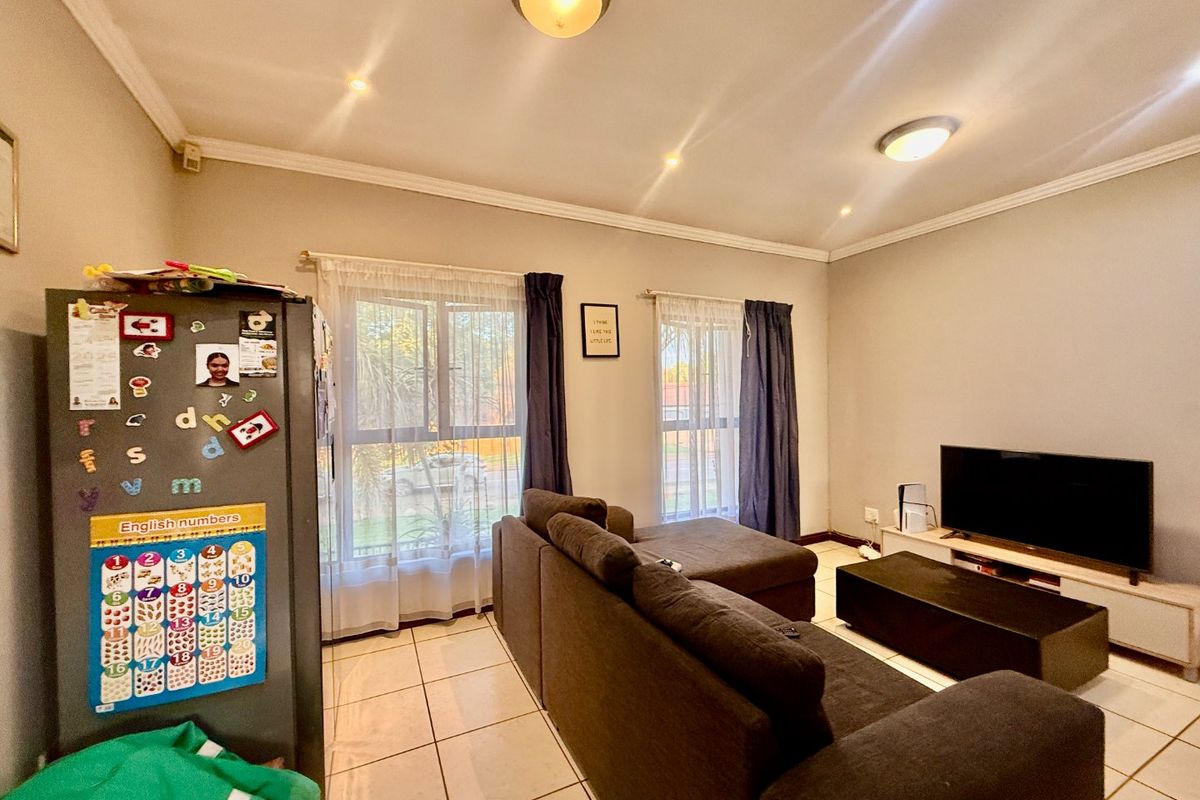 A well-lit living room featuring tiled flooring, coved cornicing, and large windows with natural light, providing a comfortable and functional living space.