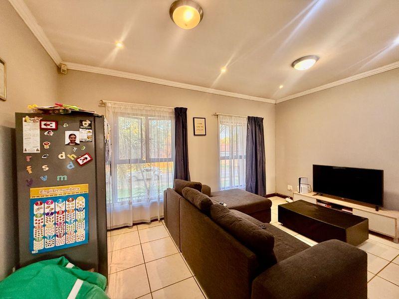 A well-lit living room featuring tiled flooring, coved cornicing, and large windows with natural light, providing a comfortable and functional living space.
