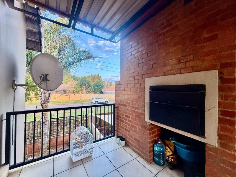 Covered balcony featuring a built-in braai, tiled flooring, and metal balustrade, offering an outdoor space suitable for entertaining.
