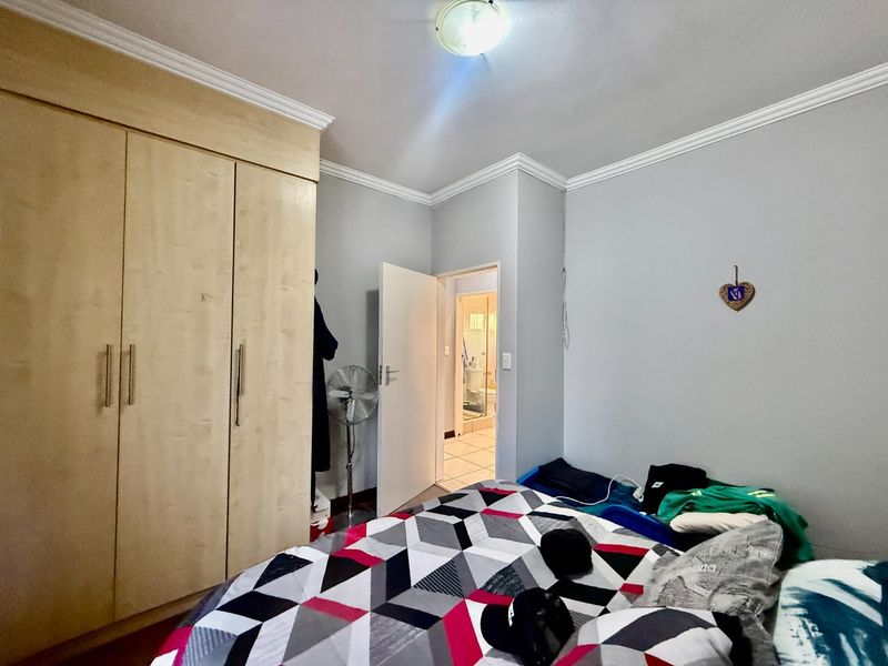 A bedroom featuring built-in cupboards, crown molding, and a view into an adjacent bathroom.