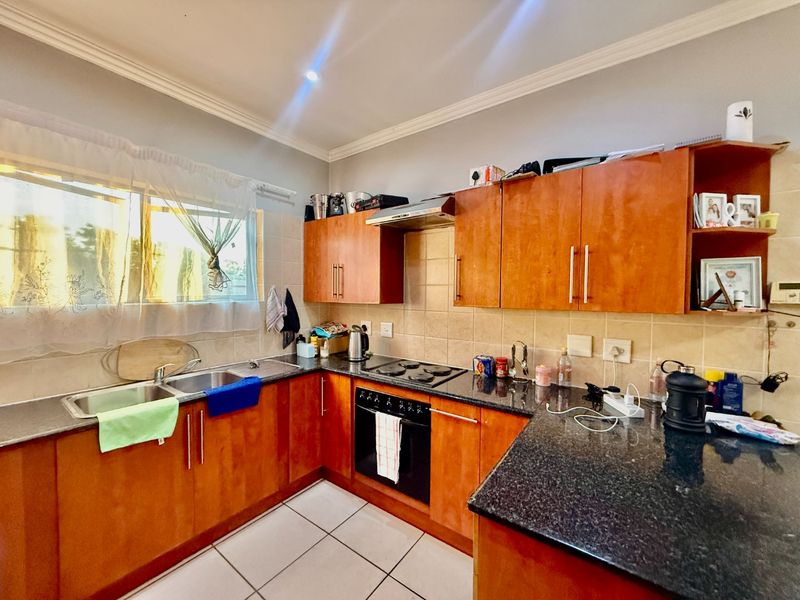 A functional kitchen featuring laminate cabinetry, granite countertops, a built-in oven with hob, and a tiled backsplash.