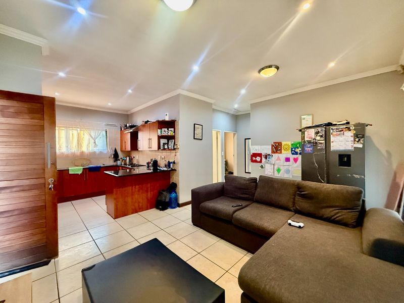 Open-plan living area featuring tiled flooring, recessed lighting, and a functional kitchen with built-in cabinetry and granite countertops.