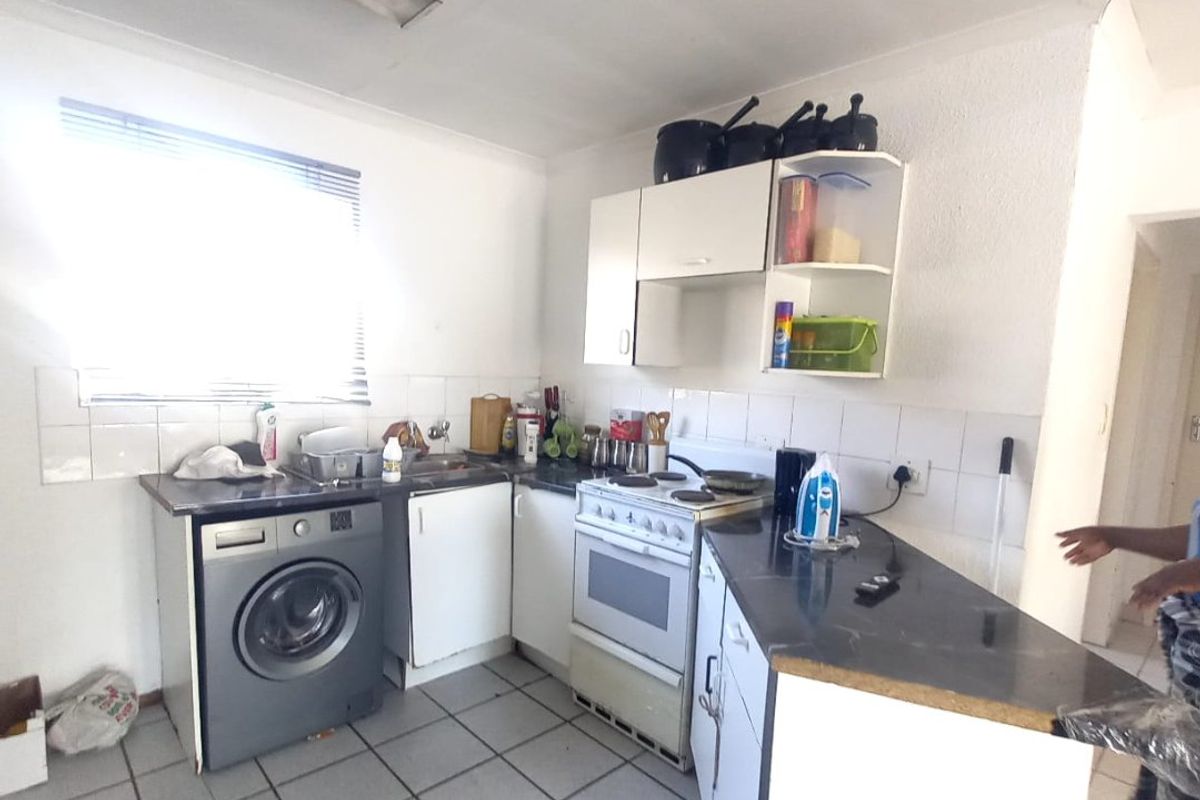 A functional kitchen featuring tiled flooring, built-in cabinetry, a tiled backsplash, and a freestanding stove, offering a practical layout for daily meal preparation.