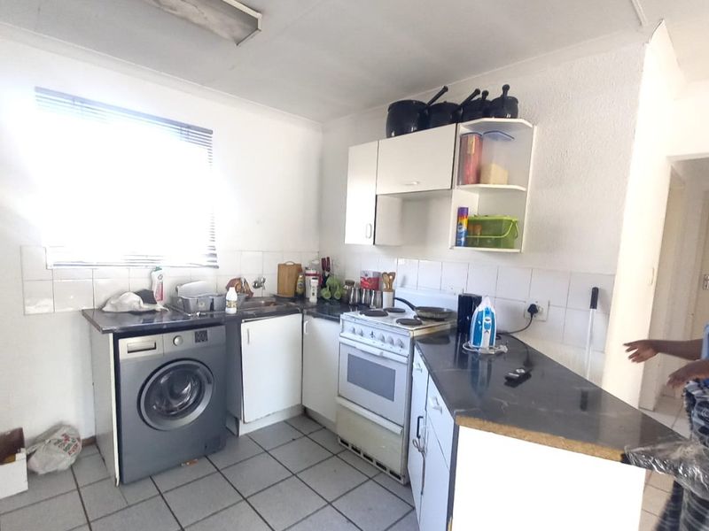 A functional kitchen featuring tiled flooring, built-in cabinetry, a tiled backsplash, and a freestanding stove, offering a practical layout for daily meal preparation.