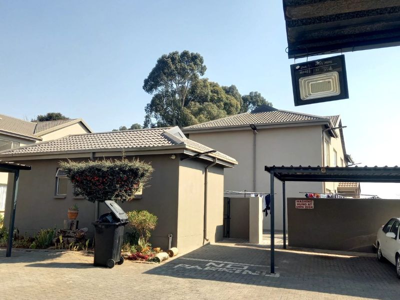 Exterior view of the apartment complex featuring a paved driveway, covered carport parking, and well-maintained building facades with tiled roofing.
