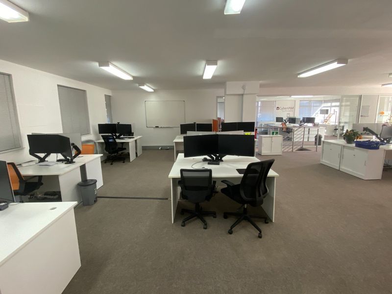 Open-plan commercial office space featuring carpeted flooring, fluorescent lighting, and glass partitions, providing a functional and professional work environment.