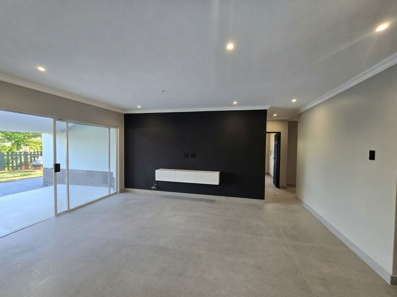 Spacious living area featuring modern tiled floors, recessed lighting, a floating media console, and large sliding glass doors leading to the patio.