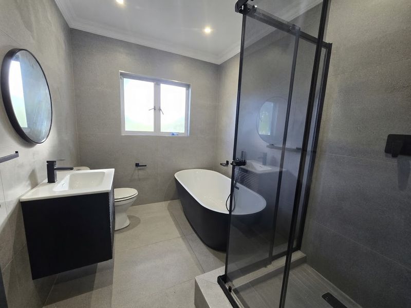 Modern bathroom featuring a sleek freestanding bathtub, a spacious walk-in shower with glass enclosure, and a contemporary vanity unit with basin.