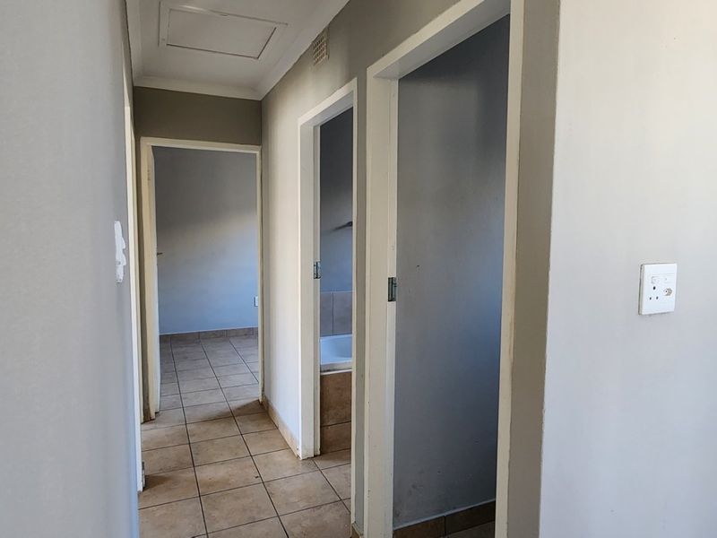 A clean, empty hallway featuring tiled flooring and access to adjacent rooms, providing a neutral foundation for interior design.