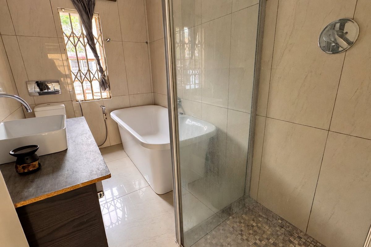 Modern bathroom featuring a freestanding bathtub, separate glass-enclosed shower, and a vessel sink vanity with tiled finishes throughout.
